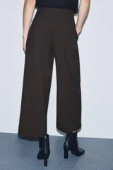 Pantalón de tiro medio confeccionado en viscosa, con corte recto y largo tobillero. Presenta cintura con trabillas, bolsillos laterales y bolsillos de vivo en la parte trasera. Cierre frontal mediante cremallera, botón y ganchos metálicos.