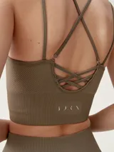 Top deportivo de sujeción media con diseño seamless y tecnología 3D. Presenta tirantes finos cruzados en la espalda y una banda elástica acanalada en la base para mayor ajuste.