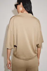 Polo de corte holgado confeccionado en mezcla de lyocell, con cuello solapa, cierre frontal de botones y mangas cortas amplias.