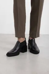 Botín asimétrico de estilo Chelsea color bordó, confeccionado en cuero vacuno, con paneles elásticos laterales negros, puntera cuadrada, suela de plataforma y tacón de bloque cuadrado.