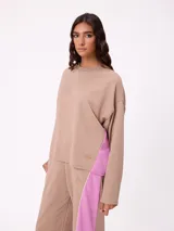 Sweater de corte oversize y estilo cropped, color beige con detalles laterales en color fucsia. Presenta cuello redondo y logo bordado en la parte inferior.
