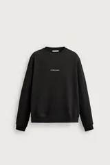 Sudadera regular fit color negro de cuello redondo y manga larga, con interior afelpado y pequeño texto estampado en contraste en el pecho.