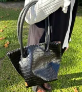 Cartera tipo shopper de cuero negro con textura crocco, silueta estructurada, manijas largas para el hombro y detalles de costura artesanal en los bordes.