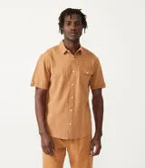 Camisa de hombre de manga corta color marrón, confeccionada en lino y algodón. Presenta cuello clásico, botonadura frontal, bolsillo en el pecho y mangas con botón para enrollar.