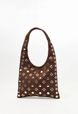 Cartera tipo hobo confeccionada en gamuza negra, con asa integrada y decorada en toda su superficie con tachas metálicas plateadas dispuestas en patrones geométricos.