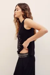 Musculosa de viscosa color blanco, sin mangas, con escote en V decorado con apliques y un gran estampado frontal de temática astrológica en tonos dorados y oscuros.