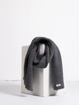 Bufanda de punto acanalado en color gris oscuro, con etiqueta de marca en uno de sus extremos.