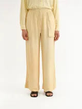 Pantalón de corte ancho, color amarillo claro, con cintura elástica fruncida y cordón ajustable. Cuenta con bolsillos frontales aplicados y dobladillo ancho en los tobillos.