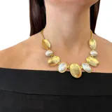 Collar corto dorado con eslabones gruesos y colgantes ovalados de bronce y perlas plásticas.