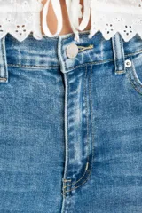 Jean de corte wide leg con tiro medio, confeccionado en denim de algodón. Presenta un diseño de pierna ancha con costuras verticales frontales que estilizan la silueta, cierre de botón y cremallera, y bolsillos clásicos.