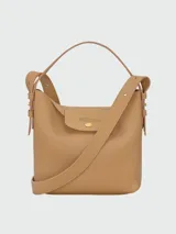 Cartera bucket S Longchamp modelo Le Cadence, confeccionada en cuero granulado color bordó. Presenta solapa frontal con botón a presión metálico dorado y grabado de la marca, asa superior de mano y correa de hombro ajustable y desmontable.