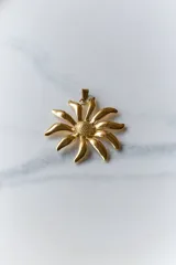 Collar con dije de acero quirúrgico en forma de flor tipo margarita con acabado dorado brillante y tiento largo de 120 cm.
