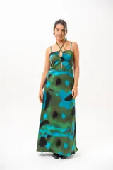 Vestido largo con estampado abstracto en tonos verdes, azules y negros. Presenta tirantes finos y cuello halter cruzado con detalle de abertura en el pecho.