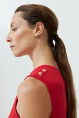 Musculosa de algodón color rojo, con cuello redondo, corte sin mangas y detalle de botones decorativos en los hombros.