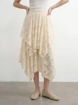 Falda midi de encaje color crema con diseño asimétrico de capas superpuestas y corte irregular.