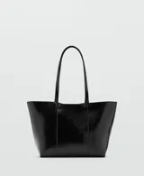 Bolso tipo shopper color negro, confeccionado en poliuretano con acabado brillante y efecto arrugado, con asas largas y costuras verticales decorativas en el frente.