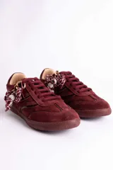 Zapatillas de gamuza color bordó con diseño de inspiración retro, cordones al tono y detalle decorativo de cordón trenzado con cuentas en los laterales.