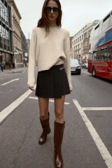 Bermuda de tiro alto color negro, con diseño de tablas frontales y detalle de eslabones metálicos dorados en la cintura. Cuenta con cierre lateral oculto.