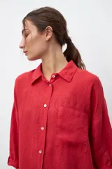 Camisa de lino color rojo, de corte oversize, con cuello clásico, cierre frontal de botones y bolsillo en el pecho.