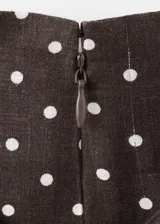 Falda midi evasé de tiro medio, confeccionada en mezcla de lino, con estampado de lunares y detalle de cinturón en la cintura.