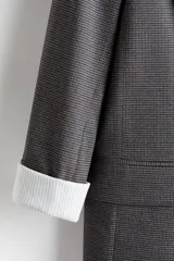 Blazer de sarga con diseño a cuadros, solapas de pico y frente abierto. Cuenta con bolsillos delanteros ribeteados con solapa y mangas diseñadas para ser remangadas, revelando un forro a rayas. Prenda completamente forrada.