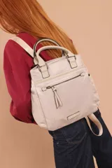 Cartera mochila de diseño versátil, color rosado, confeccionada en material sintético impermeable. Cuenta con doble asa superior, correas ajustables para usar como mochila, compartimento principal con cierre y bolsillo frontal con cierre decorado con tirador largo.