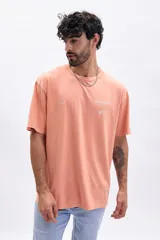 Remera de manga corta color tostado con estampado frontal en blanco que incluye texto y gráficos minimalistas.