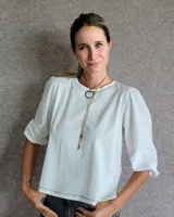 Remera de algodón con cuerpo liso y mangas abullonadas de textura diferenciada. Presenta cuello redondo y costuras decorativas visibles en el ruedo y el escote.