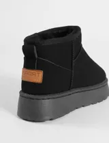 Botas cortas tipo ugg color beige, con interior forrado en corderito sintético y suela de plataforma plana.