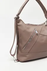 Cartera convertible en mochila, confeccionada en cuero sintético texturizado color marrón. Presenta un diseño con recortes, bolsillo frontal con cierre diagonal, herrajes metálicos plateados, asa superior y correas regulables.