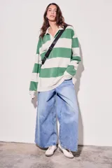 Sweater estilo polo de corte oversize, con diseño de rayas horizontales anchas en tonos camel y bordó. Presenta cuello camisero con cierre frontal parcial y mangas largas con puños ajustados.