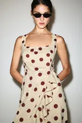 Vestido midi de mezcla de lino y viscosa en color beige con estampado de lunares bordó. Cuenta con escote recto, tirantes anchos y un volante lateral en cascada que recorre el frente hasta el bajo asimétrico.