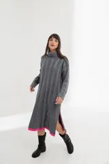 Vestido midi tejido de punto color gris, con cuello alto, manga larga y corte recto. Tiene aberturas laterales con terminación en color fucsia.