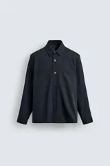 Sobrecamisa de corte relajado confeccionada en tejido de algodón con elasticidad. Presenta cuello solapa, cierre frontal con botones, manga larga con puños abotonados y dos bolsillos plastrón en el pecho.