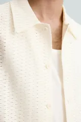 Camisa regular fit de manga corta confeccionada en tejido jacquard con estructura abierta y diseño geométrico. Presenta cuello solapa y cierre frontal con botones al tono.