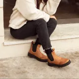 Bota de cuero color terracota, de caña media con elástico lateral y suela de neolite negra.