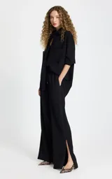 Pantalon sastrero negro de corte recto y tiro alto. Presenta cintura elástica con cordón ajustable, bolsillos laterales con ribete en contraste, pespuntes decorativos y aberturas laterales en el bajo.