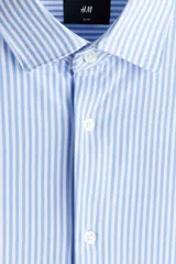 Camisa H&M de corte slim fit en mezcla de algodón con rayas finas celestes y blancas. Presenta cuello italiano, cierre frontal con botones y mangas largas.