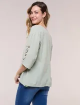 Blusa Erika de algodón con estampado de rayas en tonos azules, rosados y amarillos. Presenta cuello redondo con escote en V y botones frontales, mangas cortas decoradas con una fila de botones en los laterales y dobladillo asimétrico.