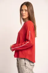 Sweater oversize rojo de algodón peinado, con mangas largas y una línea blanca decorativa a lo largo de cada manga.