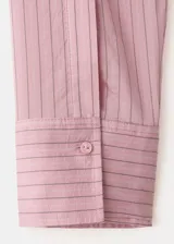 Camisa de lyocell color rosado con diseño a rayas sutiles, de corte recto, con cuello camisero, manga larga y cierre frontal de botones.