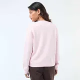 Cárdigan de punto color rosa, con cuello redondo, cierre frontal de botones dorados y puños acanalados.