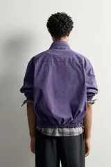 Cazadora relaxed fit de algodón en color violeta, con efecto lavado, cuello subido, cierre frontal con cremallera y bolsillos de vivo en la cadera.