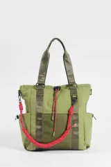 Bolso tipo shopper color verde oliva, con compartimento principal con cierre, bolsillos laterales, bolsillo frontal de red y tiras ajustables. Incluye asas de hombro y una correa decorativa trenzada en tono fucsia.