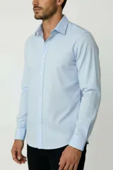 Camisa blanca de algodón, de diseño holgado y manga larga, con cuello camisero y cierre frontal de botones.