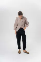 Pantalón de gabardina azul marino, de corte barrel y tiro bajo, con detalles en pana marrón en la pretina y en el ruedo interior vuelto.