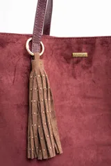 Charm para bolso compuesto por flecos de cuero sintético color marrón, decorados con pequeñas tachas metálicas doradas. Incluye un aro y un cierre de mosquetón metálico en tono dorado.