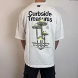 Remera de corte oversize color blanco con estampa gráfica en la espalda que incluye hongos y texto en color negro y verde.