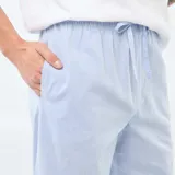 Pijama de dos piezas compuesto por una remera blanca de manga corta con bolsillo frontal y un pantalón largo de color azul claro, confeccionado en tela de popelina.