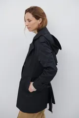 Trench coat negro de corte midi, con cuello solapa, cierre frontal cruzado con botones y cintas ajustables en los puños.